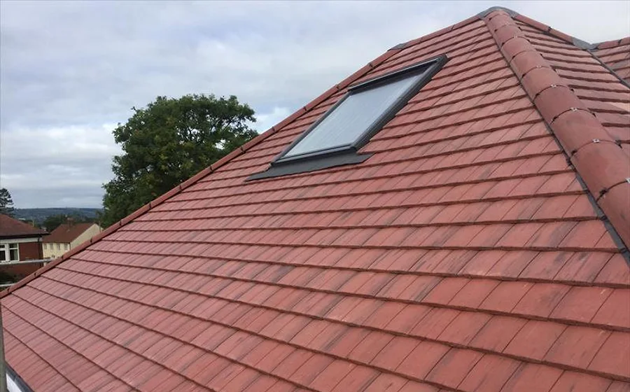 A genuine Newline new roof — fresh plain-tile pitched roof with a roof window
